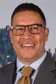 Headshot of a middle aged man with brown skin and glasses