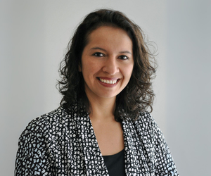 Woman with curly hair looking at the camera with black and white blazer