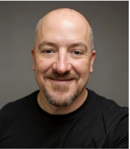 bald man with a mustache in a black sweater