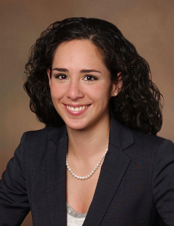 woman with curly hair and pearls in a black blazer