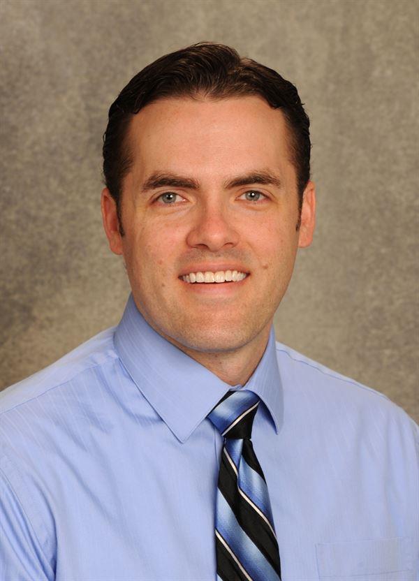 Man in blue shirt with black and blue striped tie