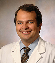 middle age man with brown hair and a slight gap in his teeth in a lab coat