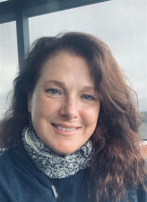 middle age woman with blue eyes, a slight head tilt, and long wavy hair