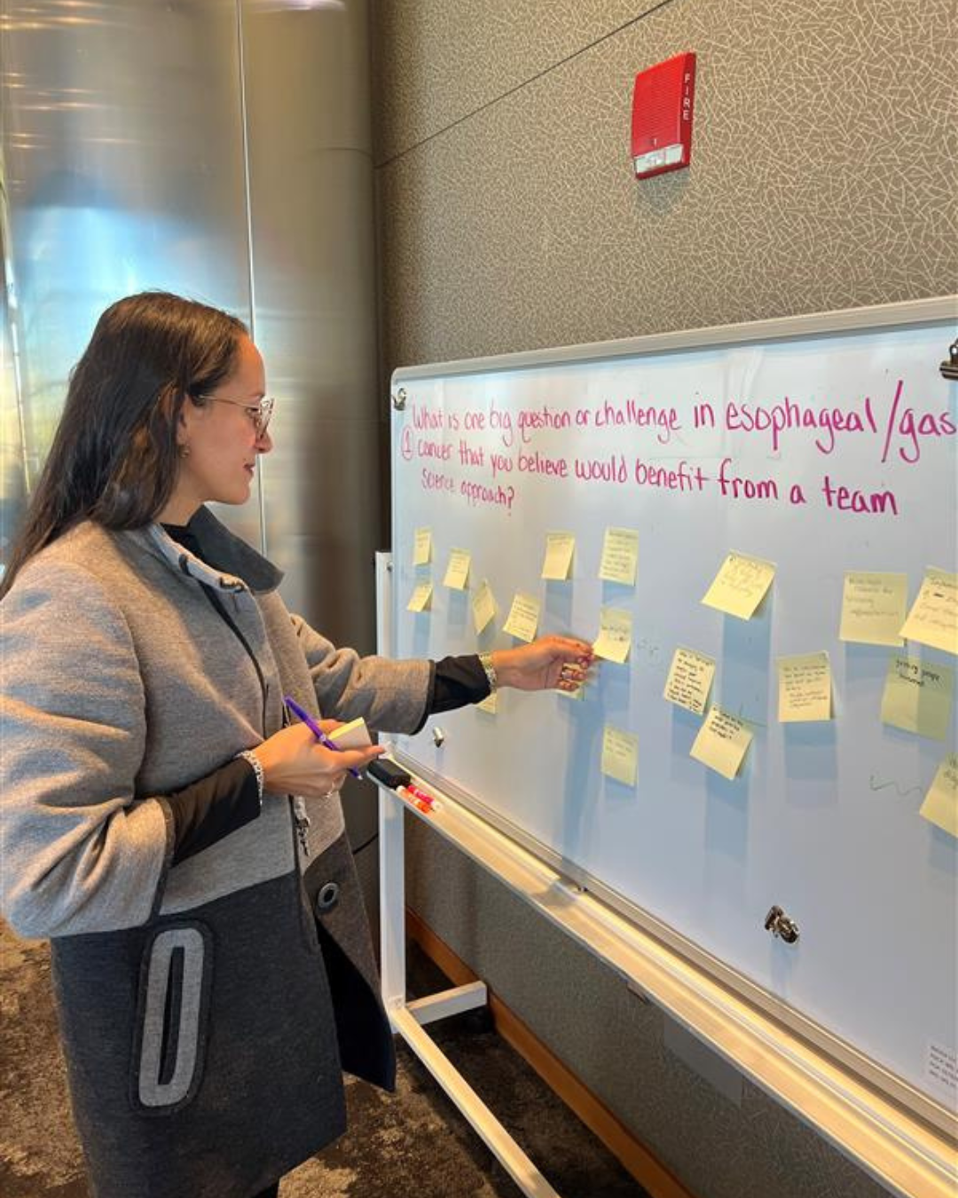 Brunette woman at whiteboard covered with post it notes
