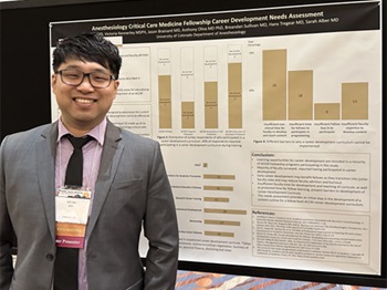 A doctor stands next to a research poster
