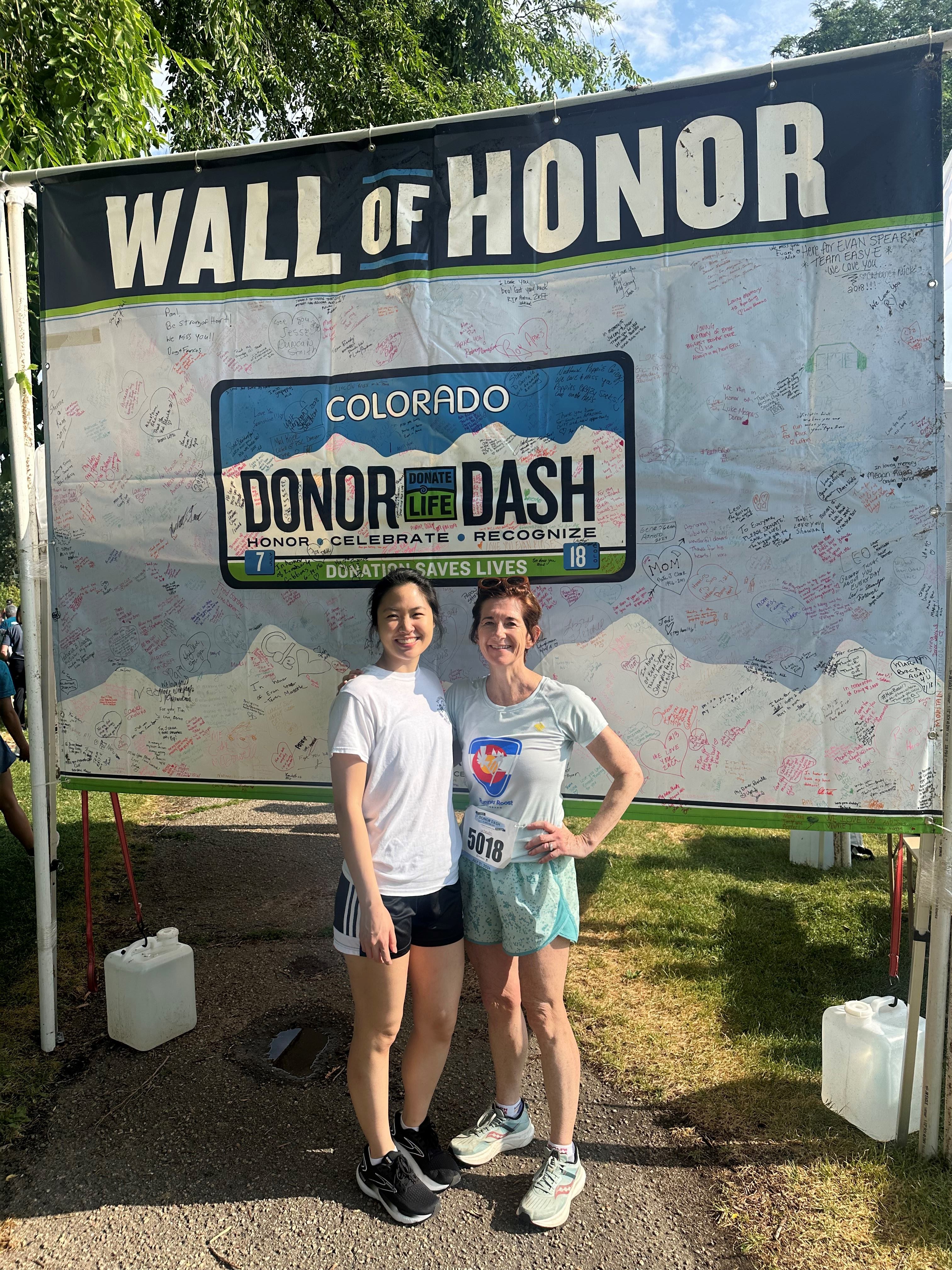 Dr. Luu and Dr. Zwald standing in front of the Donor Dash poster after finishing their 5k race