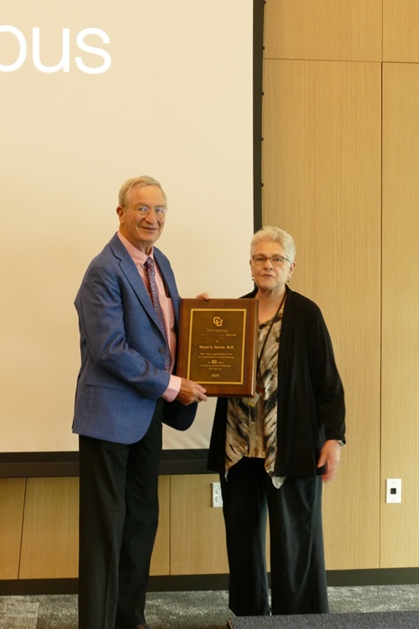 Dr. Cheryl Armstrong presenting David Norris a plaque of appreciation for 50 years of service