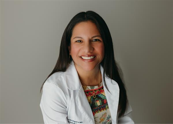 A professional picture of Carla Torres-Zegarra, MD smiling and wearing a white coat