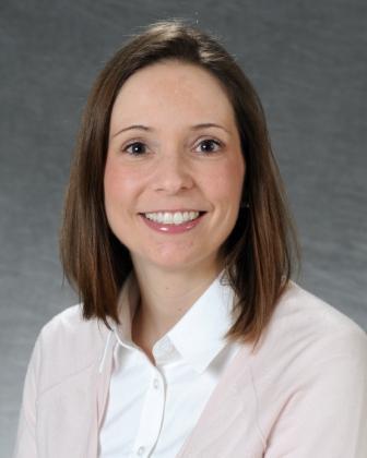 Sabrina Newman's professional headshot, smiling and wearing a pink sweater over a white button up shirt