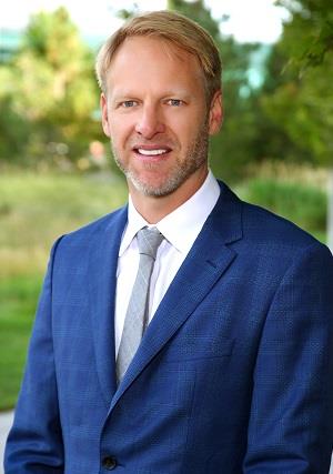 Professional headshot of Erik Hink,MD standing outside in a blue suit