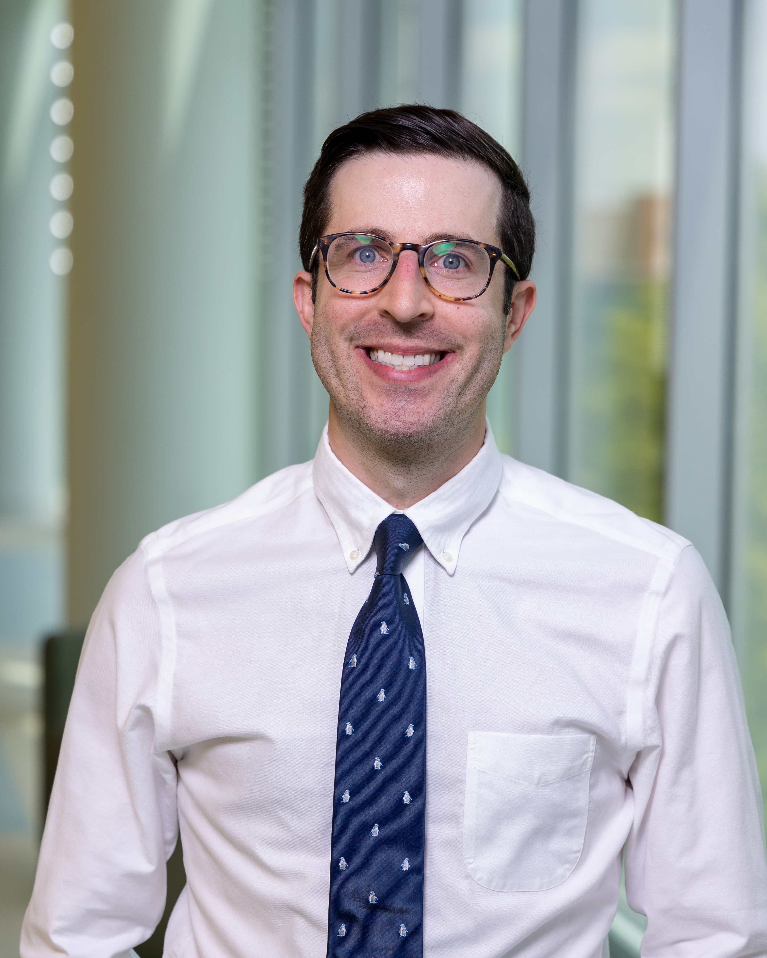 Grant Plost, MD, professional headshot, smiling and wearing a white button up shirt.