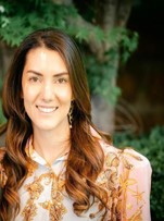 Professional photo of Sofia Guelfand-Warnken, MD, smiling while sitting in front of trees