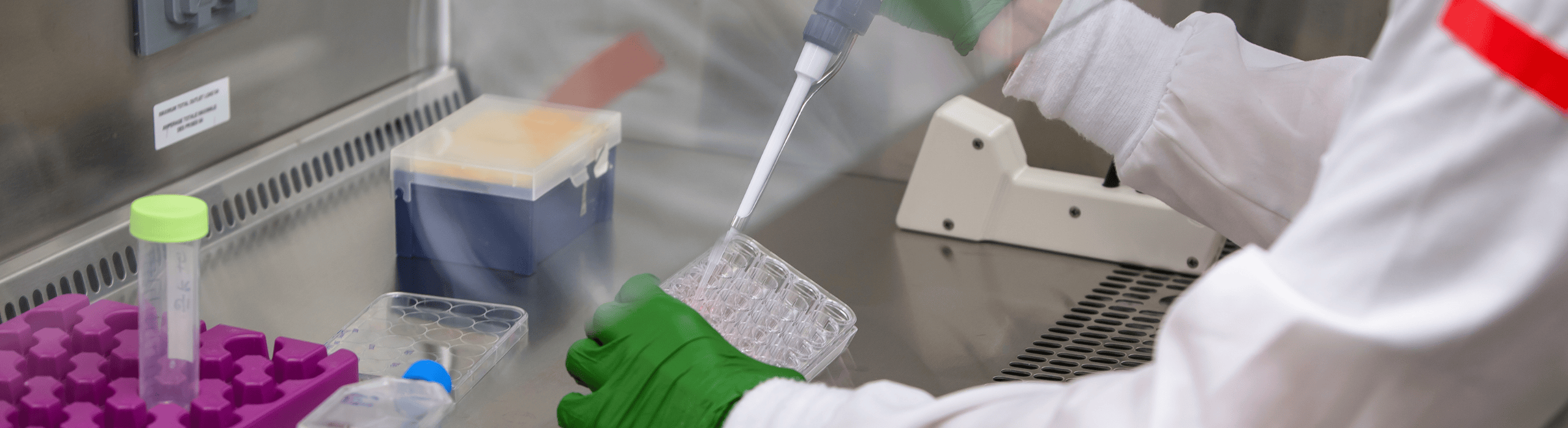 Handswithgreenglovesusingapippettetofilltunesinaventalatedspace