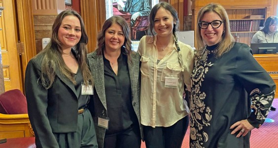 STEMPosterDayattheCapitolorganizersGabrielleVragelKosteleckyandElizabethSpearposewithColoradoSenatorDafnaMichaelsonJenetrightinthestateSenatechambersPhotocourtesyofRachaelKostelecky