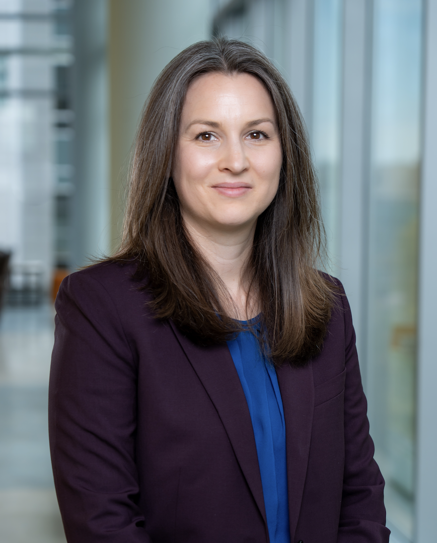 female with a maroon blazer, headshot in a well lit hallway
