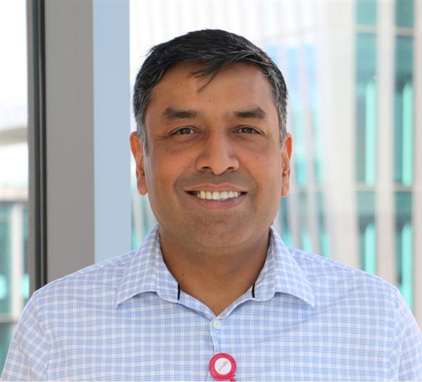 doctor headshot, smiling, with a light blue/white button down shirt