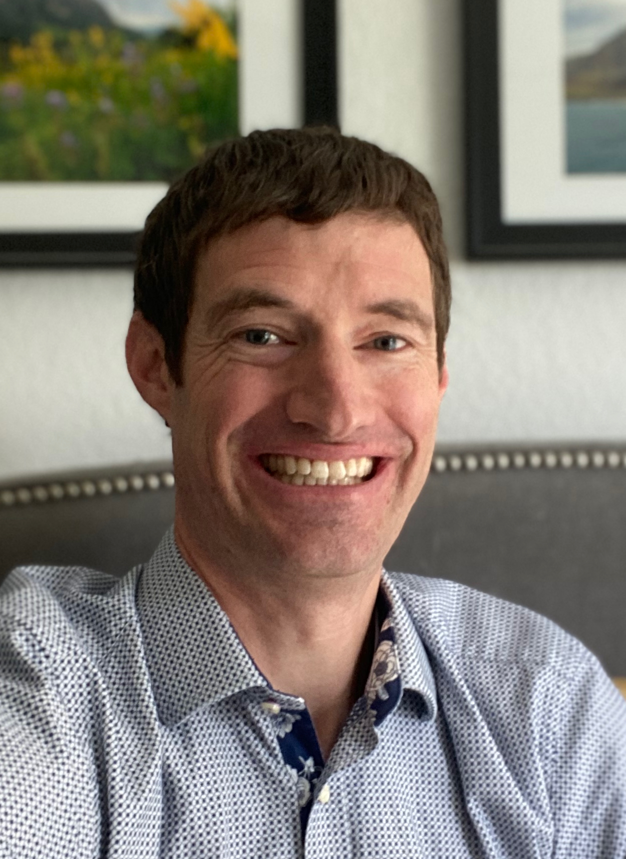 male smiling with a blue and white striped shirt for a headshot photo