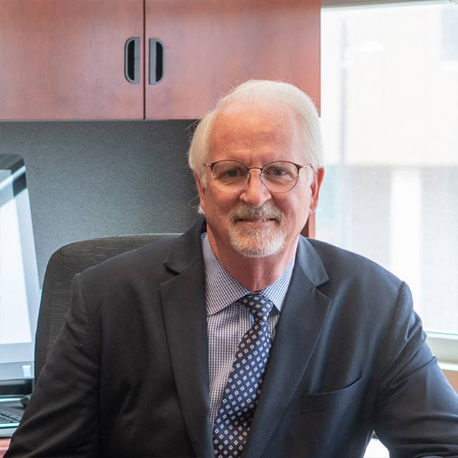 man smiling with glasses and a grey suit