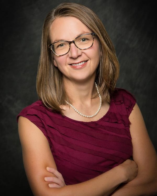 female doctor smiling in a maroon blouse