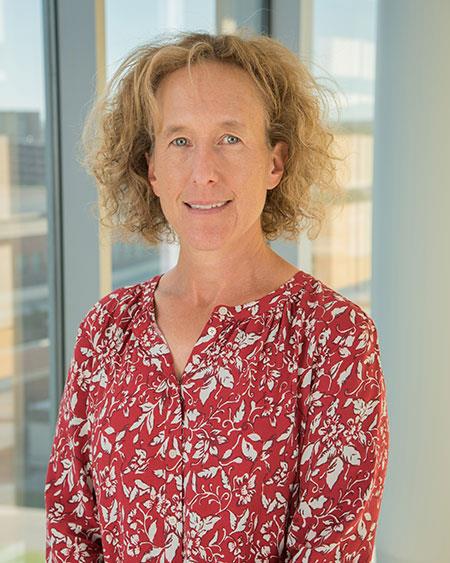 female with blonde hair and a red shirt with white floral, smiling