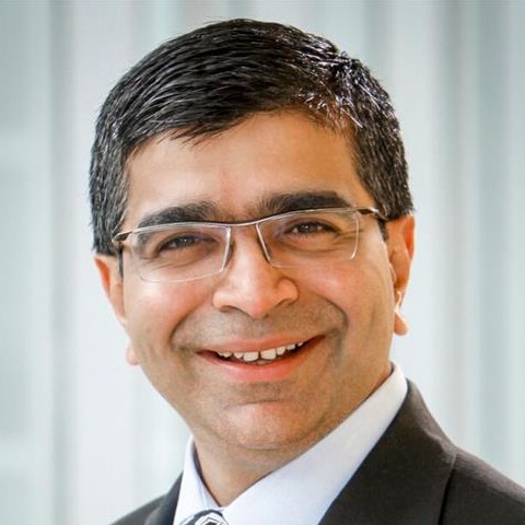 man smiling with a suit on and glasses for a headshot
