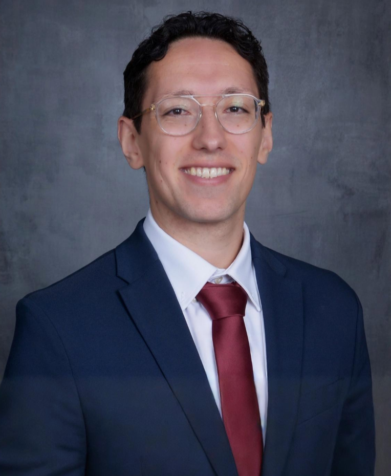 man smiling with glasses and blue suit with a red tie