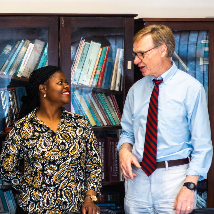 three people standing behind a bookcase smiling and interacting