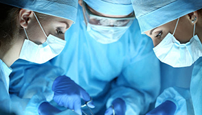Three surgeons, head together over patient