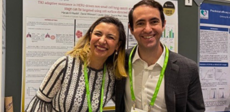 Kyle Concannon, MD posing in front of his poster presentation with a colleague.