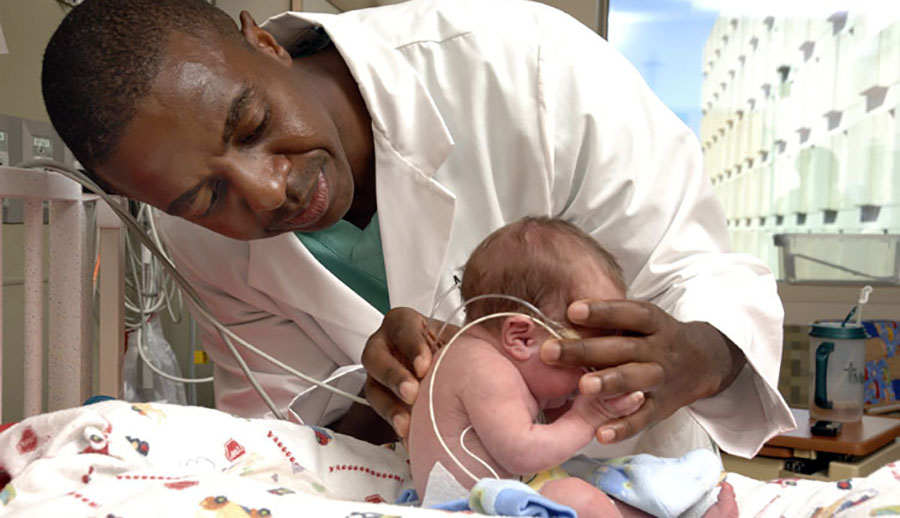 pediatrician with stethoscope and very small baby