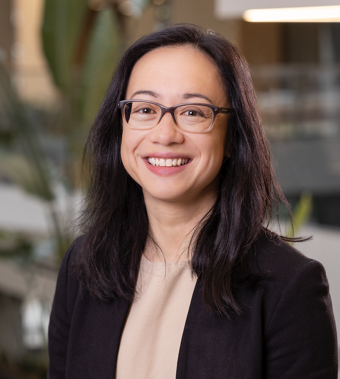 female doctor with glasses, black blazer, and pink blouse