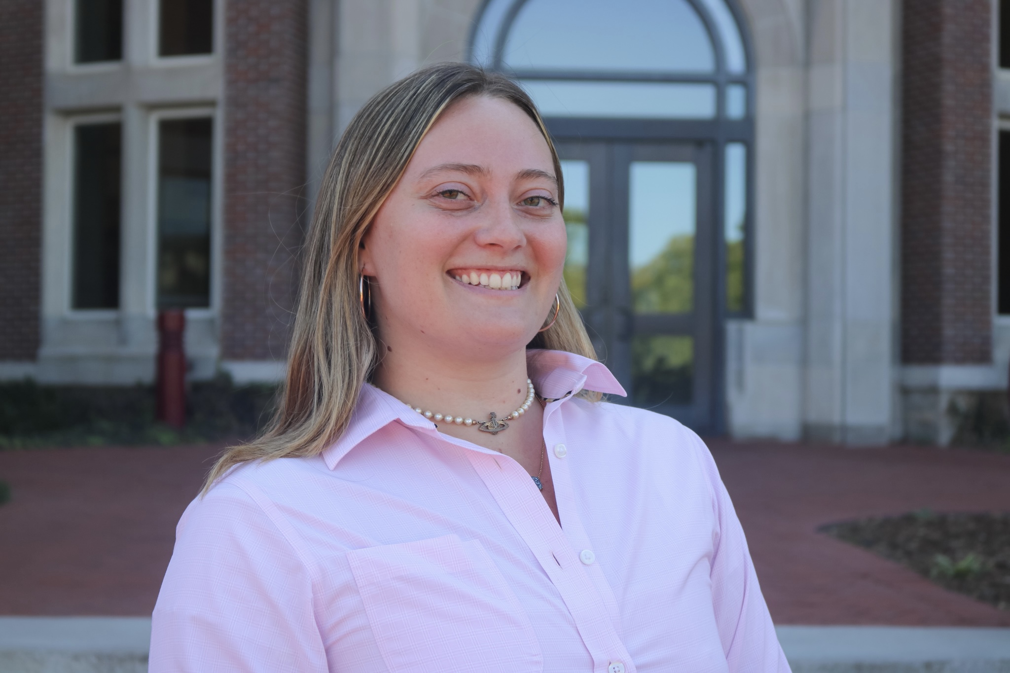 female smiling with a pink long button down shirt