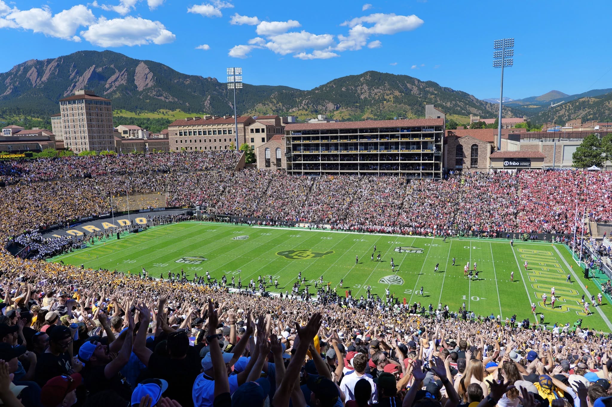 Folsom Field in Boulder, Colorado packed with fans, with the Flatirons behind the stadium