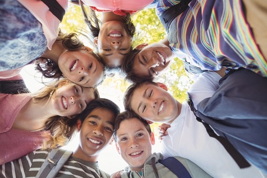 Portrait of smiling school kids forming a huddle in campus at school