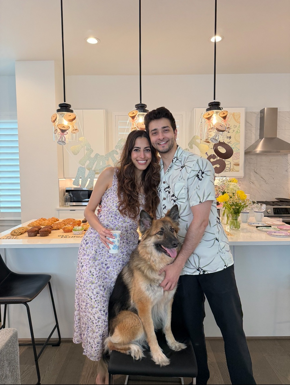 Dr. Shah hugging a person and a dog in a kitchen.