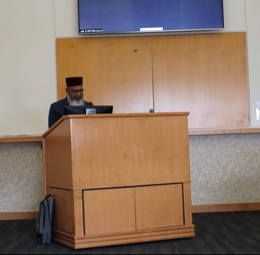 Dr. Ghulam Qadir Fayyaz speaking behind podium in a conference room