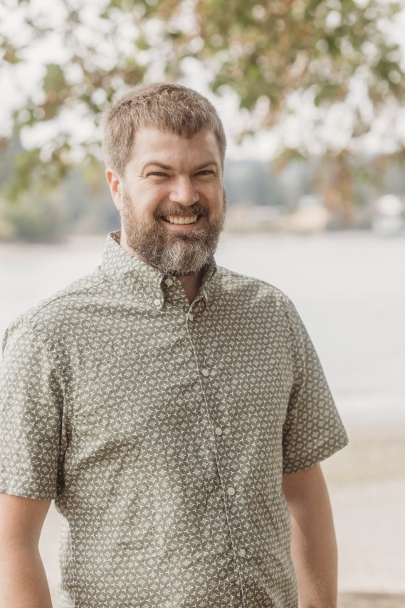 Photo of a man outside smiling in a short sleeved collared shirt