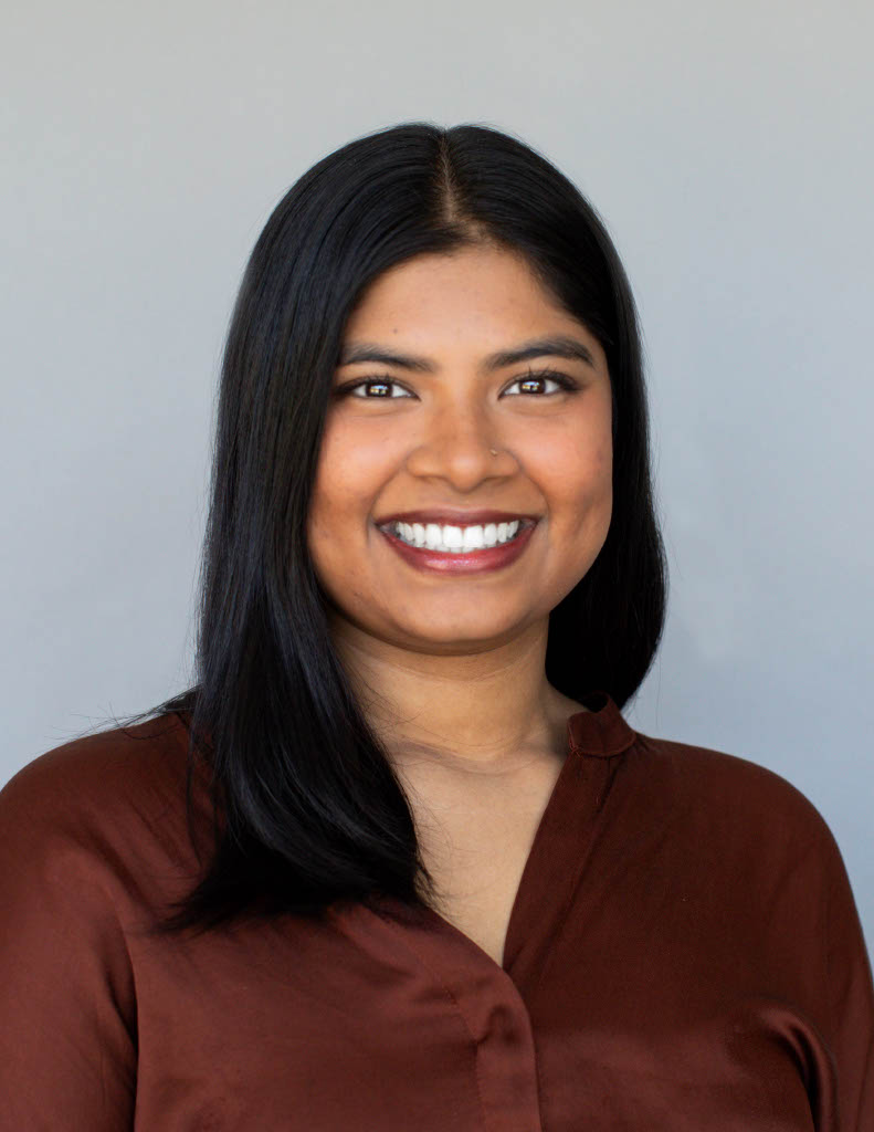 Professional headshot of a women in a collared shirt with a plain grey background.