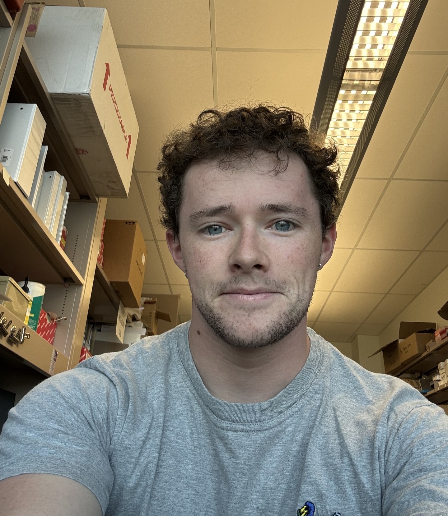 Selfie photo of a man in a t-shirt taken in side a laboratory storage are.
