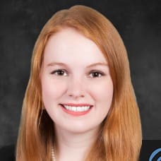 Headshot of woman with plain greay/black backdrop in the background