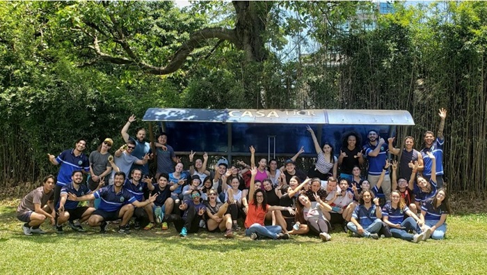 A group photo of students raising their hands in a tropical setting.