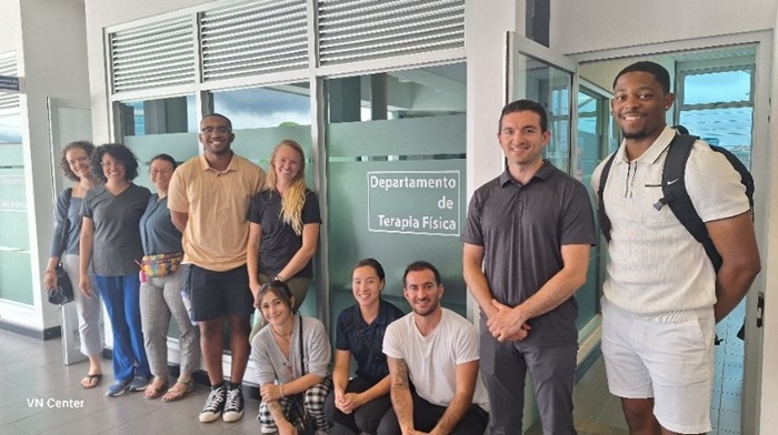A group photo of PT students next to a sign in Spanish.