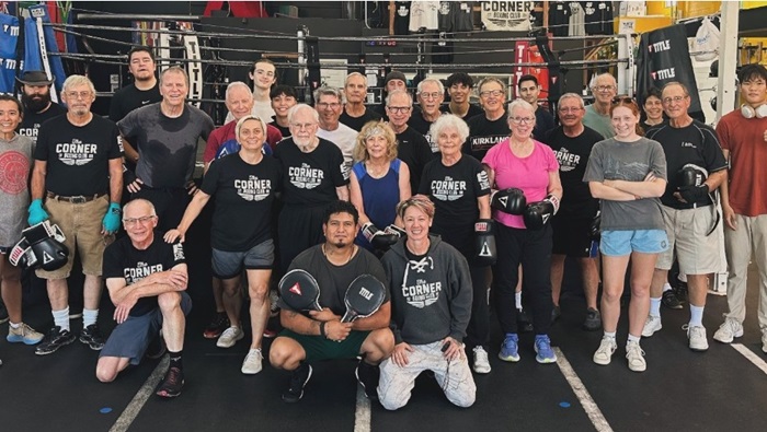 A group photo of people in a boxing gym.