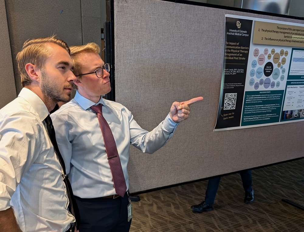 Photo of two male students pointing at a poster.