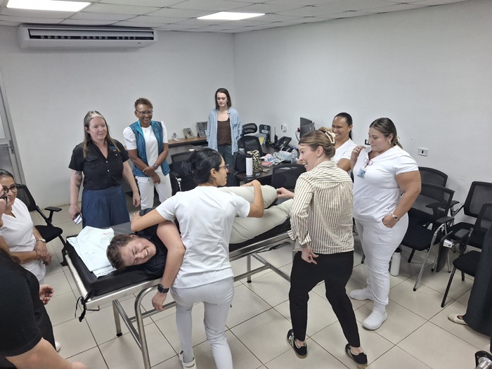 PT students and medical staff practicing skills on a medical table.