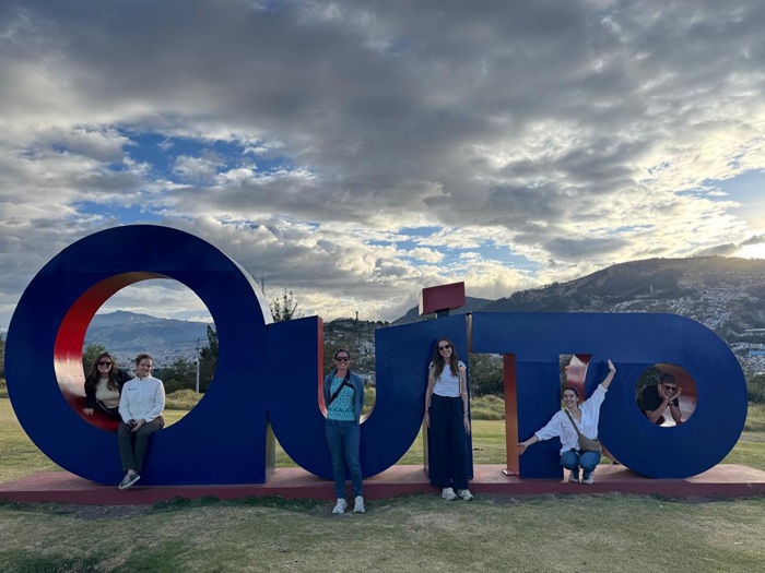 Students and faculty in front of a Quito, Ecuador sign.