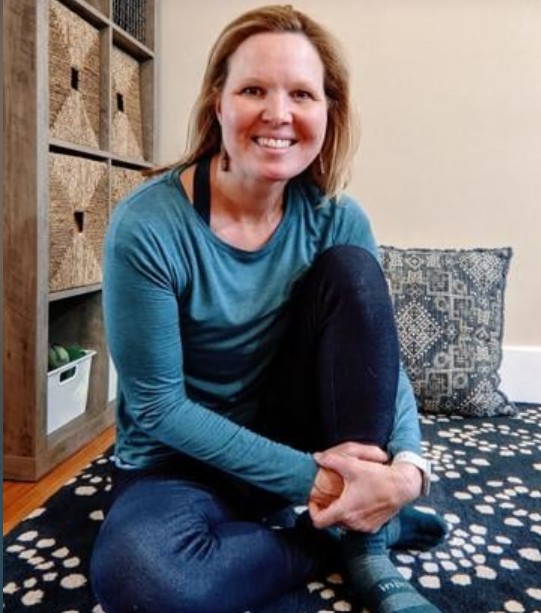 Joanna Zaremba sitting on a floor in a room.