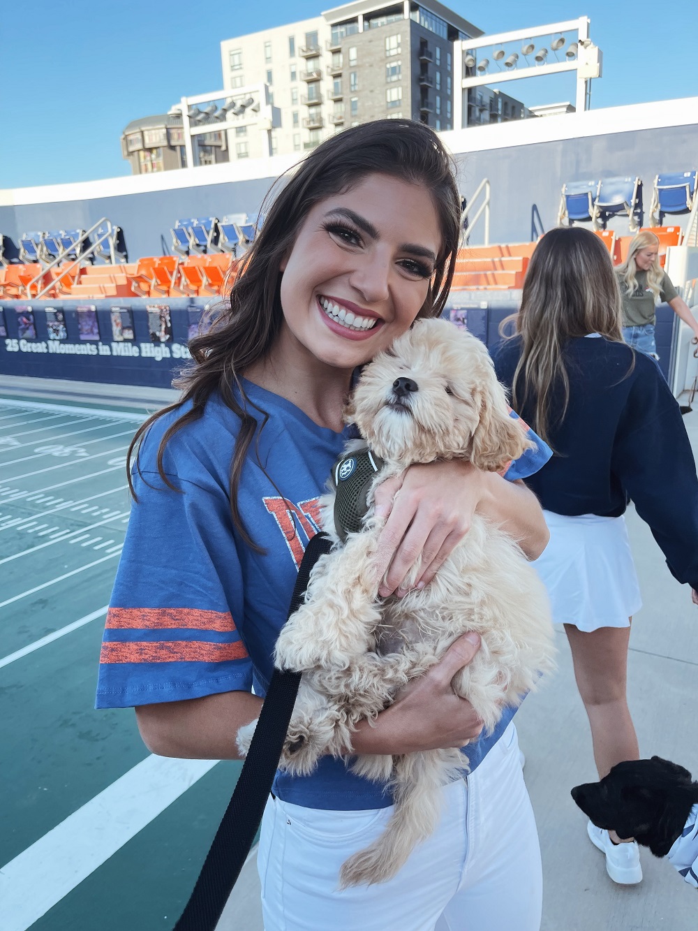 Photo of Renee Jones holding a dog on football field.