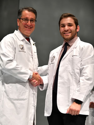 PA student in a white coat shaking hands with the program director