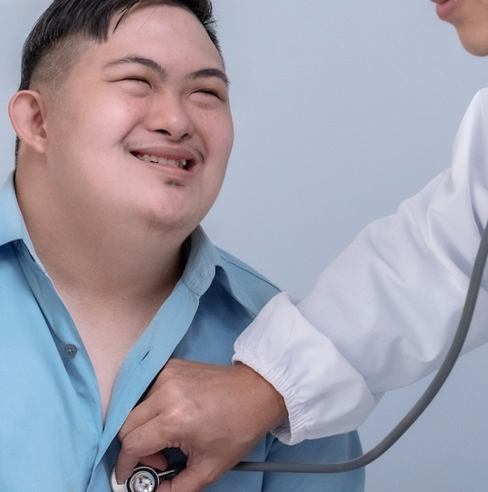 Man with Down syndrome and doctor listening to his heart with a stethoscope